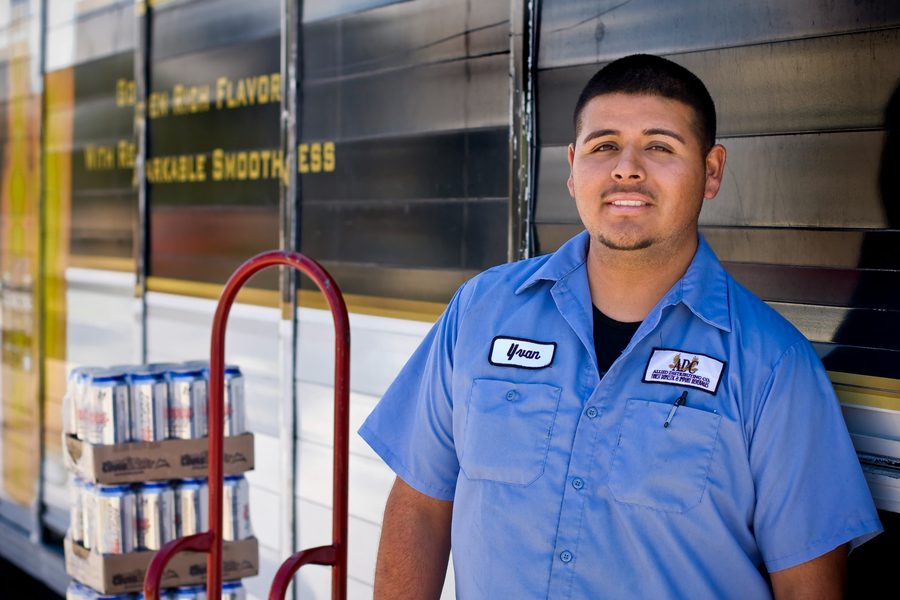 Delivery driver in a company work shirt beside his truck with a load of cases