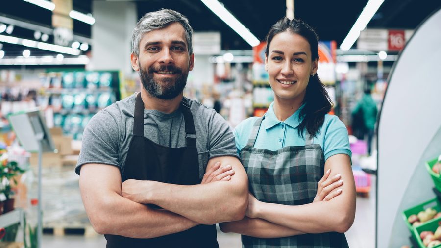 Two grocery store workers in aprons on the shop floor